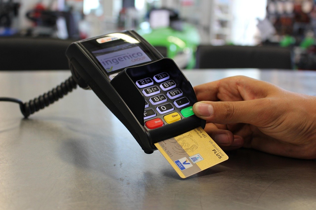 Close-up of a customer paying with a credit card at a card terminal, illustrating the American Express workforce cut announced with its third-quarter 2026 results